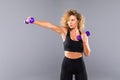 Portrait of pretty curly sporty girl holding weights dumbbels isolated on gray background Royalty Free Stock Photo