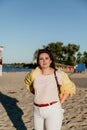 Beautiful plus size woman in yellow jacket on sandy beach