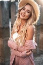 Portrait of a pretty, cute and romantic smiling girl with long loose blonde hair in a straw hat. Countryside landscape, sunlight a Royalty Free Stock Photo