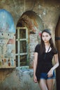 Portrait of a pretty dark-haired girl on the background of an old building. Antique architecture on the background