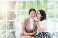 Portrait of pretty daughter kissing on the cheek and embracing her mother while there is sitting on white sofa in living Royalty Free Stock Photo