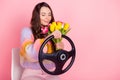 Portrait of pretty dreamy girl holding in hands smelling tulips driving invisible car fast delivering isolated over pink Royalty Free Stock Photo