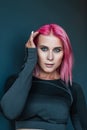 Portrait of a pretty fashionable woman with pink hair and blue eyes in black sportswear posing against a dark background Royalty Free Stock Photo