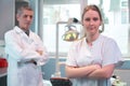 Portrait of pretty female dentist arms crossed with colleague standing in background Royalty Free Stock Photo