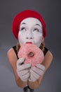 Portrait of pretty female mime eating a tasty pink Royalty Free Stock Photo