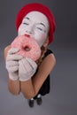 Portrait of pretty female mime eating a tasty pink Royalty Free Stock Photo