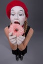 Portrait of pretty female mime eating a tasty pink Royalty Free Stock Photo