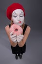 Portrait of pretty female mime eating a tasty pink Royalty Free Stock Photo