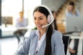 Portrait of pretty female online agent wearing white headset having conversation with client during telephone call at customer Royalty Free Stock Photo