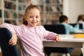 Portrait of pretty female school pupil, sitting at desk in classroom, turning back and smiling at camera, free space Royalty Free Stock Photo