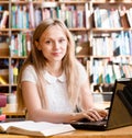 Portrait of a pretty female student with laptop in library Royalty Free Stock Photo