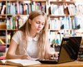 Portrait of a pretty female student with laptop in library Royalty Free Stock Photo