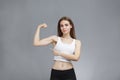 Woman shows her muscular arms over gray background