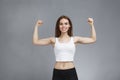 Woman shows her muscular arms over gray background