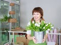 Portrait of pretty florist woman with white tulips at a flower shop. Royalty Free Stock Photo