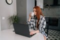 Portrait of pretty freelancer female enjoying cup of coffee while remote working or studying on laptop computer sitting Royalty Free Stock Photo