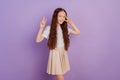 Portrait of pretty friendly little girl hands show two v-signs posing on purple background