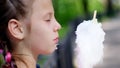 portrait, pretty girl of eight years, blonde, with freckles, and multi-colored pigtails, eats sweet white cotton, cotton Royalty Free Stock Photo