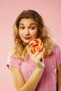 Portrait of a happy pretty girl holding sweet candy over pink ba Royalty Free Stock Photo