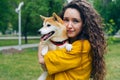 Portrait of pretty girl loving dog owner standing in park with her beautiful pet smiling