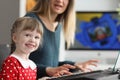 Pretty happy kid learns how to play on piano with mother