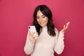 Portrait of pretty happy person using phone isolated on the pink background.