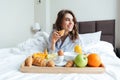 Portrait of a pretty happy woman having breakfast in bed Royalty Free Stock Photo