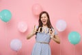 Portrait of pretty happy young woman in blue dress blinking holding wooden word letters love on pink background with