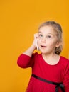 Portrait of a pretty joyful girl in red dress talking on mobile phone isolated over yellow background Royalty Free Stock Photo