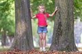 Portrait of a pretty little child girl standing near big tree trunk in summer park outdoors Royalty Free Stock Photo