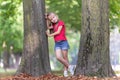 Portrait of a pretty little child girl standing near big tree trunk in summer park outdoors Royalty Free Stock Photo