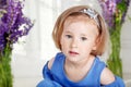 Portrait of pretty little emotion girl among violet flowers.Clouse up picture of beautiful girl