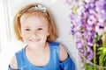 Portrait of pretty little emotion girl among violet flowers.Clouse up picture of beautiful smiling girl
