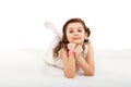 Portrait of a pretty little fun fashion girl lying on a fluffy r Royalty Free Stock Photo