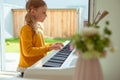 Portrait of pretty little girl having piano lesson at modern white e-piano Royalty Free Stock Photo