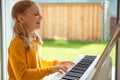 Portrait of pretty little girl having piano lesson at modern white e-piano Royalty Free Stock Photo