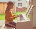 Portrait of pretty little girl having piano lesson at modern white e-piano Royalty Free Stock Photo