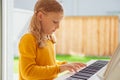 Portrait of pretty little girl having piano lesson at modern white e-piano Royalty Free Stock Photo