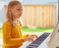 Portrait of pretty little girl having piano lesson at modern white e-piano Royalty Free Stock Photo