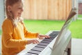 Portrait of pretty little girl having piano lesson at modern white e-piano Royalty Free Stock Photo