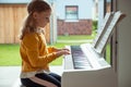 Portrait of pretty little girl having piano lesson at modern white e-piano Royalty Free Stock Photo