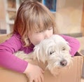 portrait of a pretty little girl playing in a box with her little dog Royalty Free Stock Photo