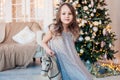 Pretty little girl posing on antique rocking horse against cozy interior with Christmas tree. Royalty Free Stock Photo