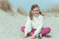 Portrait of pretty little girl sitting on white sand in dunes on Baltic sea Royalty Free Stock Photo