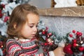 Portrait of pretty little girl touches a Christmas toy at home