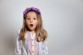 Portrait of pretty little girl  in white dress and purple wreath on gray isolated background. Royalty Free Stock Photo