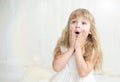 Portrait of pretty little girl in white dress , she is surprised and put her hands on cheeks. Royalty Free Stock Photo