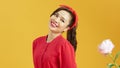 Portrait of a pretty lovely young girl casually dressed standing isolated over yellow background, near peony flower Royalty Free Stock Photo