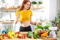 pretty nice woman with lots of healthy fresh food in kitchen. Concept of losing weight, sports and healthy eating