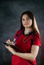 Portrait of pretty nurse woman wear red uniform holding clipboard isolated on black Royalty Free Stock Photo